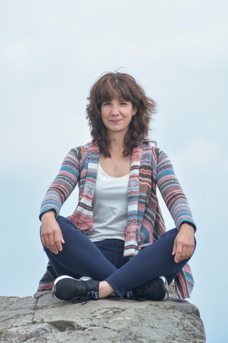 Poträt einer lächelnden Frau in der Natur, offene, herzliche Ausstrahlung vor grünem Hintergrund. LebensFunkeln - Persönlichkeitsentwicklung